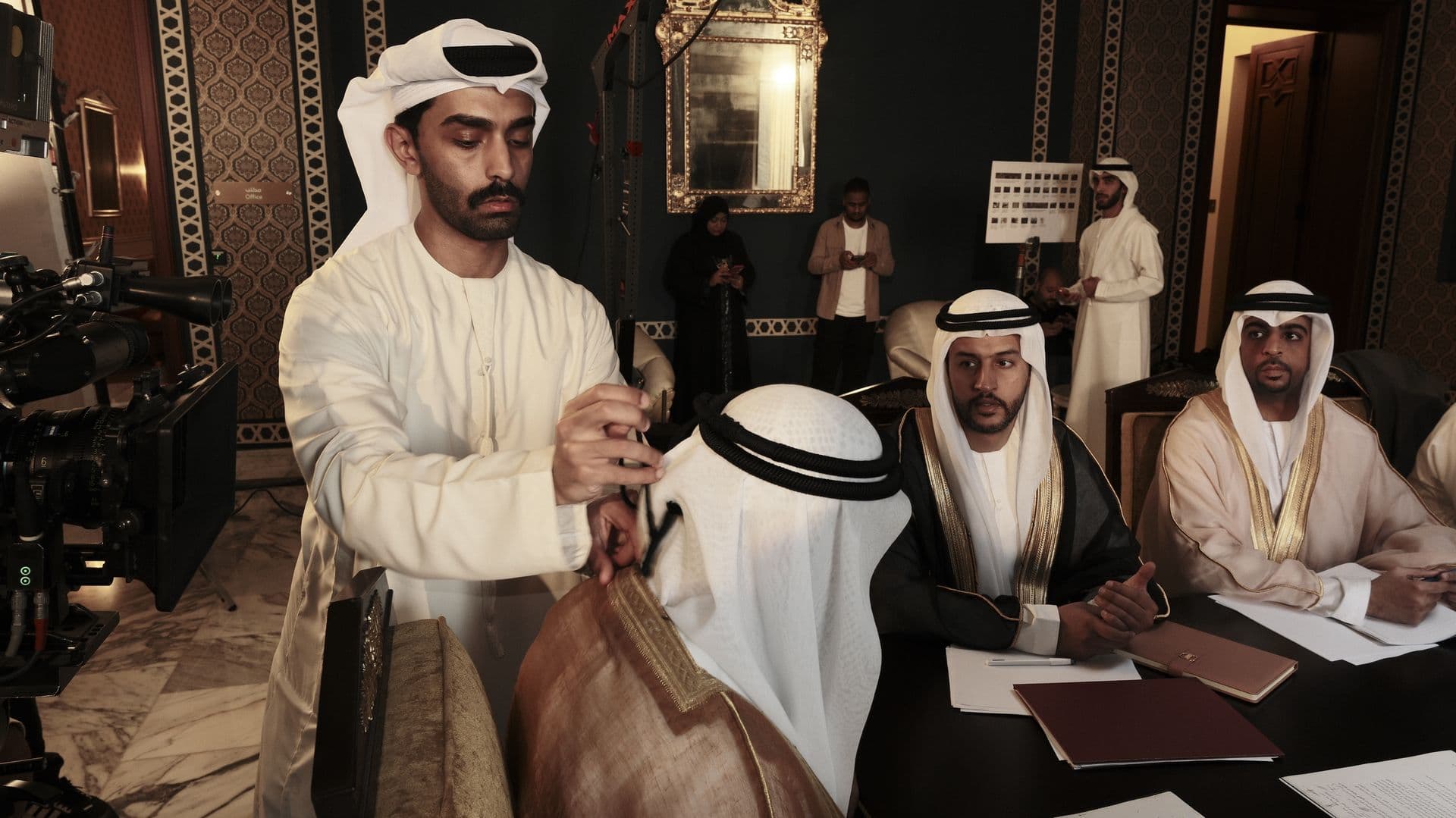 A man in a kandura reaching across the negotiation table