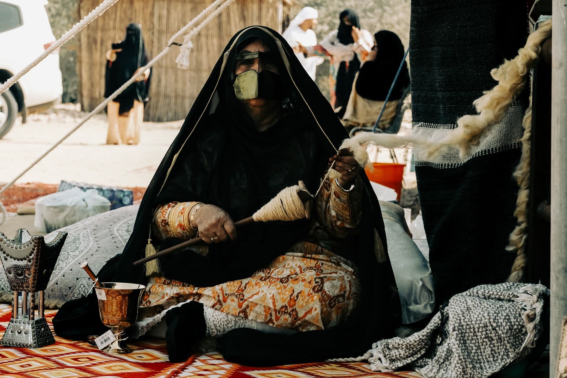 The same woman spinning wool on set under a tent